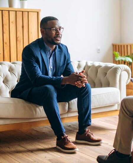 A man sitting on the edge of a couch and talking during a psychotherapy session